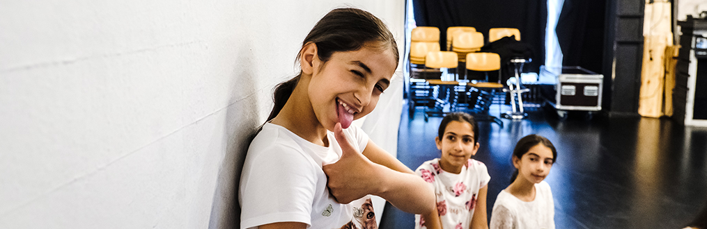 Prävention und Kindeswohl Ein lachendes Mädchen mit erhobenem Daumen