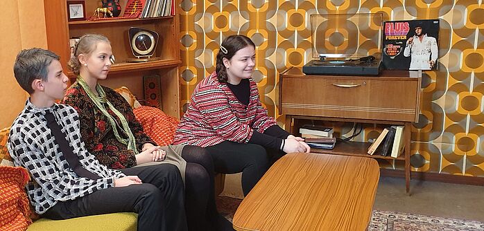 TheaterAG Gitta und ihre Eltern Drei Kinder spielen Theater und sitzen in einem Wohnzimmer