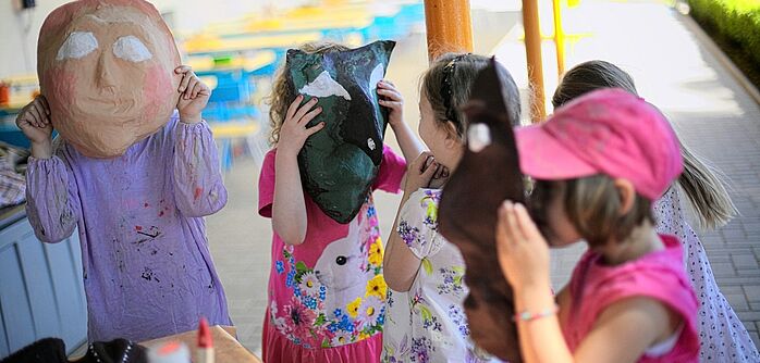 Vogtland Kinder Masken Eine handvoll Kinder halten sich Masken vors Gesicht