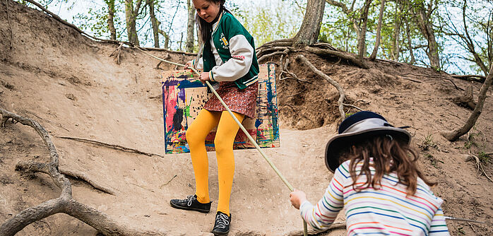 Projekt WaWiTo in Mecklenburg-Vorpommern Zwei Kinder klettern an einem Abhang, ein Kind hält ein gemaltes Bild in der Hand