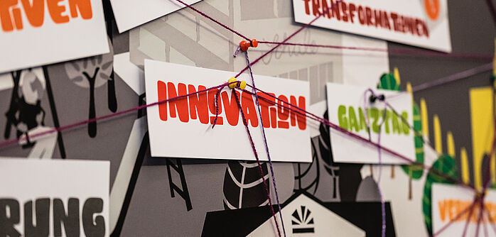 Ein Ausschnitt von einem Stadtplan mit öffentlichen Gebäduen wie Bibliothek und Musik. Darauf sind Stecknadeln befestigt, die mit Wollfäden verbunden sind. 